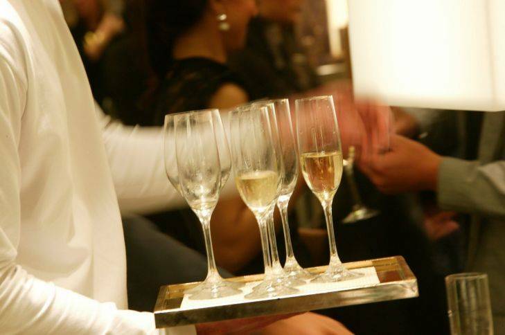 A waiter holding a tray of champagne glasses. File photo