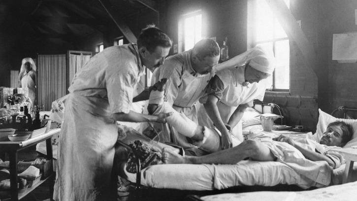 Medical staff apply a dressing to the leg of a wounded World War I French soldier at a mobile hospital south-west of Amiens. Photo: Australian War Memorial