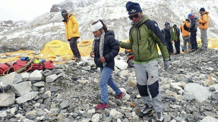 A man helps an injured woman after she is checked by a doctor at the International Mount Guide camp at Everest Base Camp on Sunday.  An avalanche triggered by Nepal's massive earthquake slammed into a section of the Mount Everest base camp on Saturday, killing 19 people, reportedly including one Australian.  Photo: Azim Afif