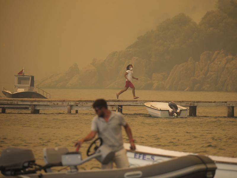Tourists and residents have fled Bodrum, in Turkey, by boat as wildfires raged in the area.