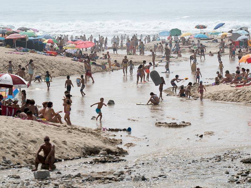 People at Portugal's Paredes beach cool off as a heat wave grips the region.
