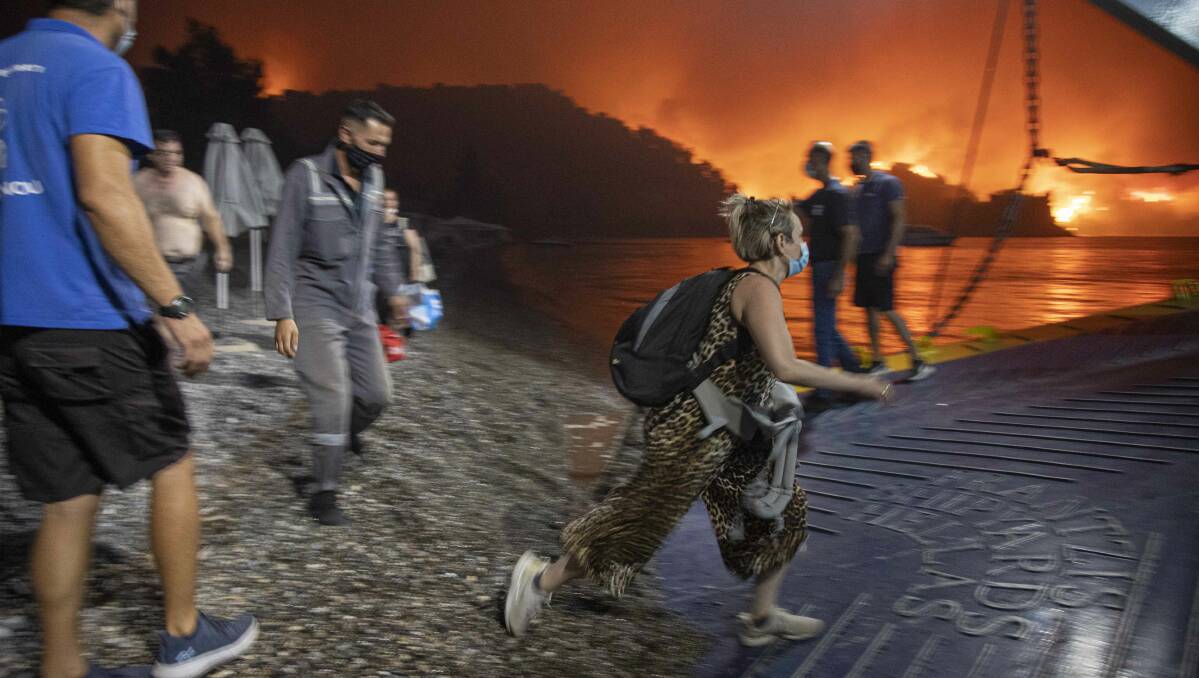 People board a ferry prior to an evacuation as a wildfire approaches the seaside village of Limni on the island of Evia, Greece, on Friday. Picture: Getty Images